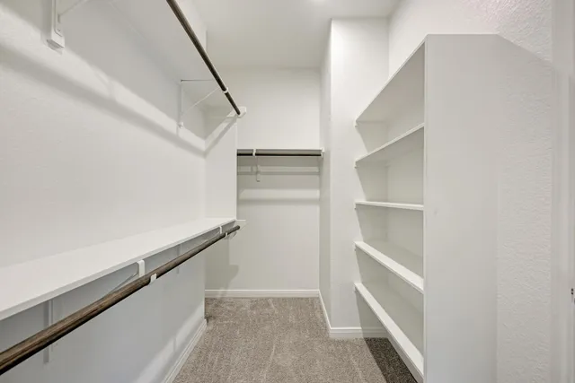 a view of an empty room with wooden floor and a ceiling fan