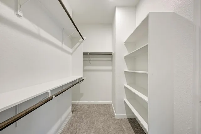 a view of an empty room with wooden floor and a ceiling fan