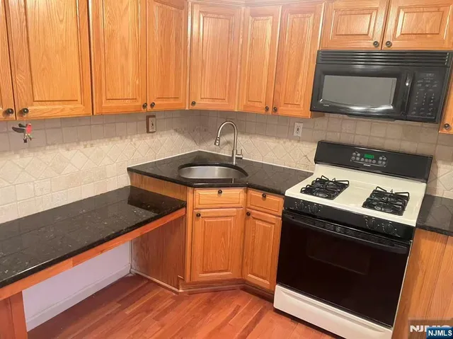 a kitchen with granite countertop wood cabinets stainless steel appliances and a sink