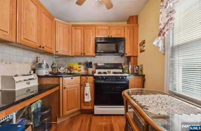 a kitchen with stainless steel appliances granite countertop a stove top oven a sink dishwasher and a refrigerator with wooden floor