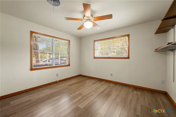 a view of an empty room with a window and a ceiling fan