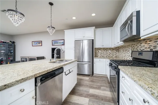 a kitchen with granite countertop white cabinets stainless steel appliances and a sink