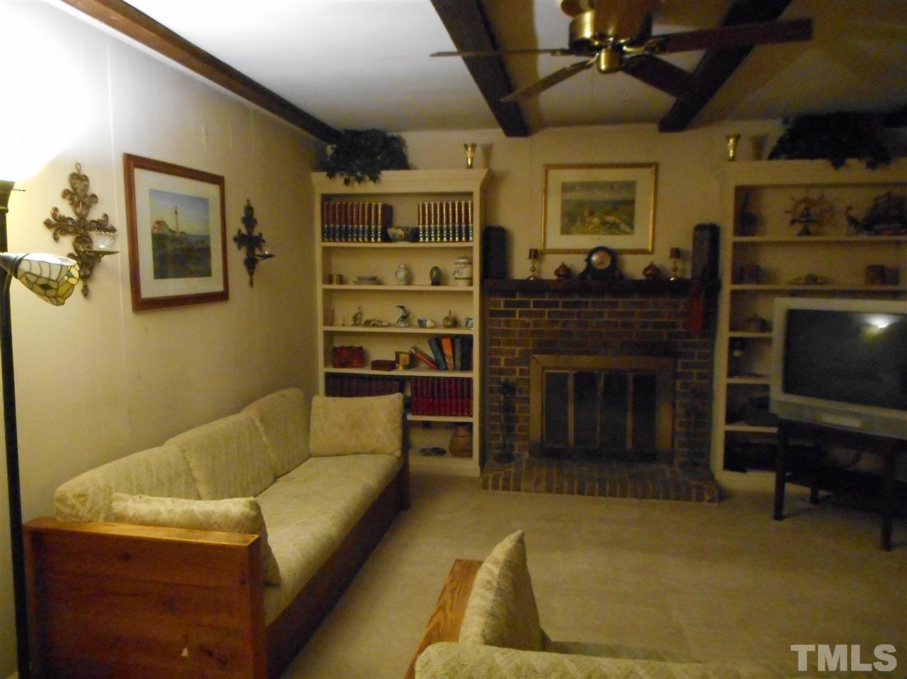 5811 Newhall Road Durham, NC 27713 - Photo 5 of 6 a living room with furniture a flat screen tv and a fireplace