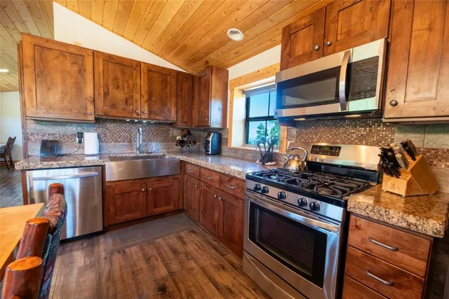 a kitchen with stainless steel appliances granite countertop a stove a sink dishwasher and microwave with wooden floor