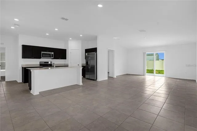 a view of living room kitchen with stainless steel appliances kitchen island granite countertop a refrigerator and a stove top oven