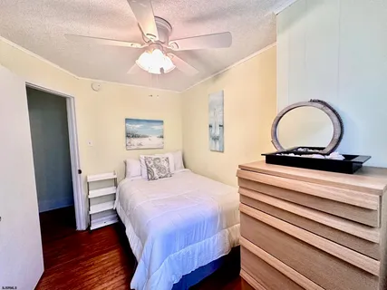 a bedroom with a bed and a dresser with wooden floor