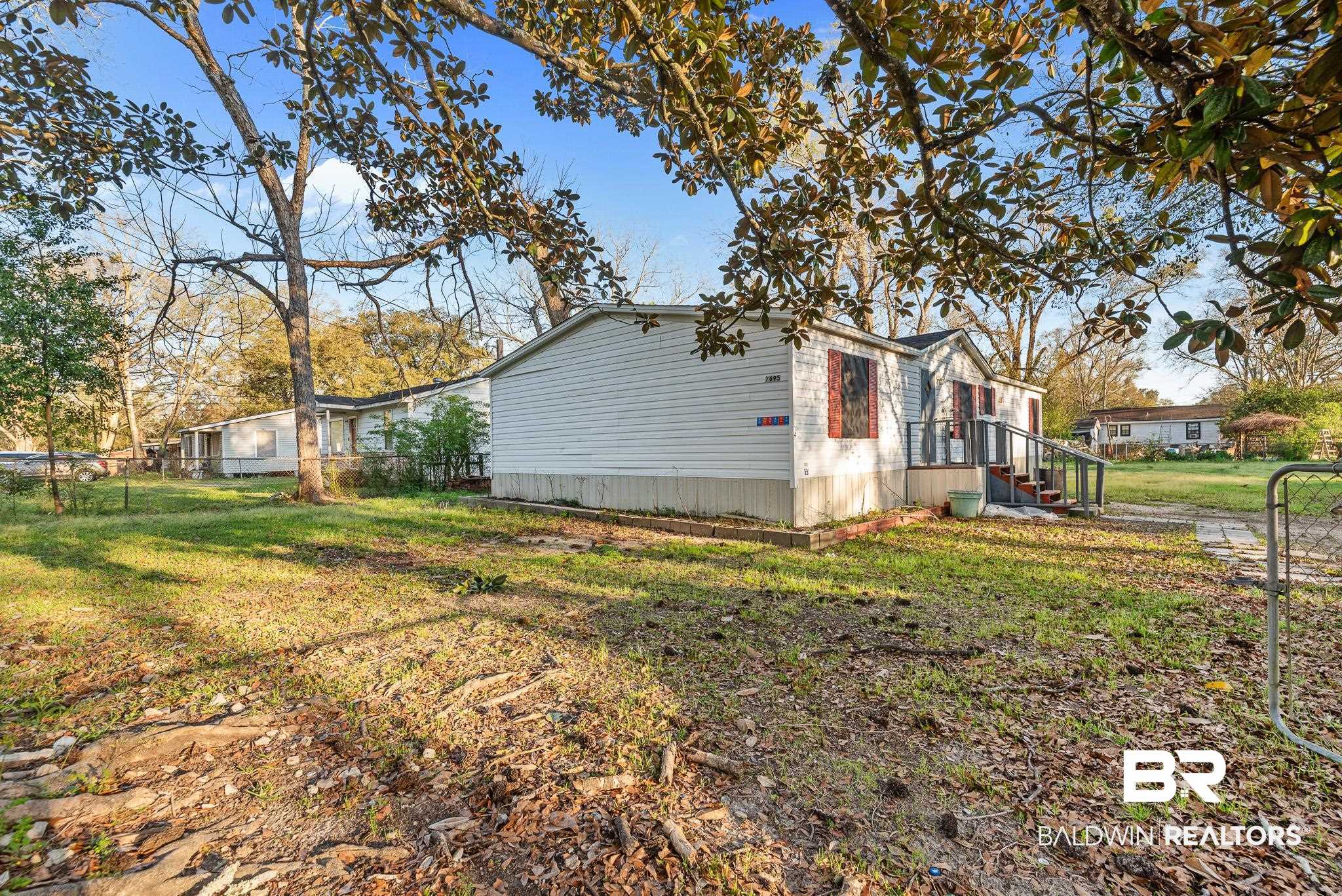 7695 Bermuda Drive Semmes, AL 36575 - Photo 2 of 27 View of property exterior featuring a lawn and fence