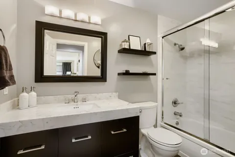a bathroom with a toilet a sink a glass door a shower a mirror and vanity