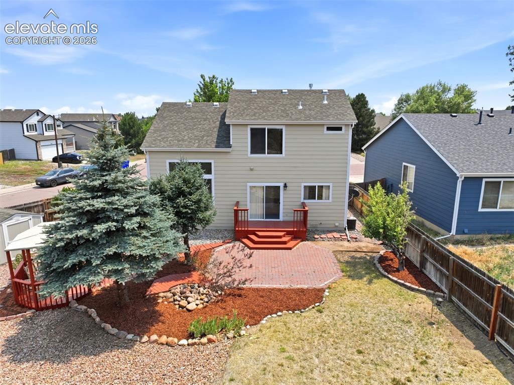7904 Coffee Road Peyton, CO 80831 - Photo 42 of 48 Rear exterior featuring a red-stained deck, brick patio, and mature landscaping