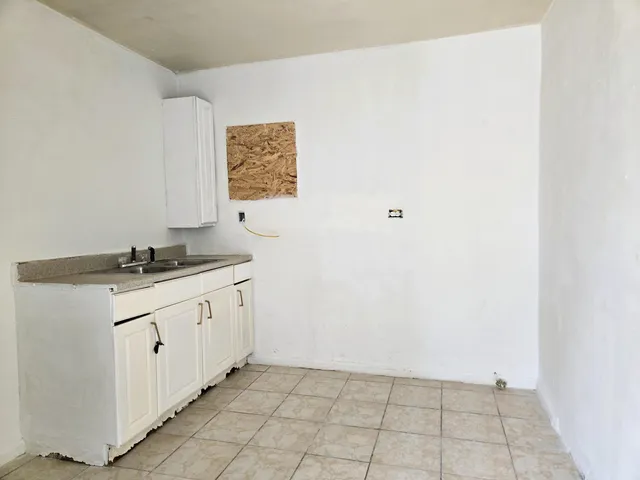 an empty room with chandelier fan and windows