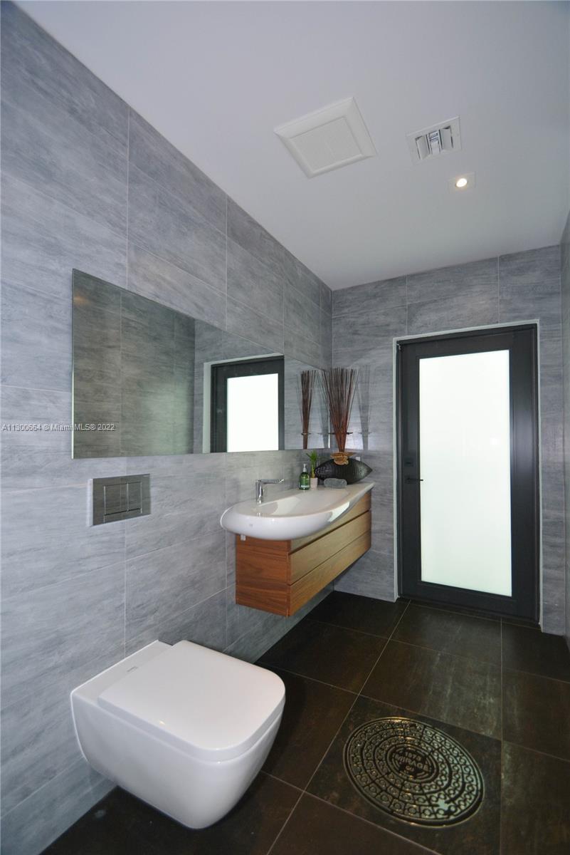 4560 Bay Point Road Miami, FL 33137 - Photo 22 of 40 a bathroom with a toilet a sink and mirror