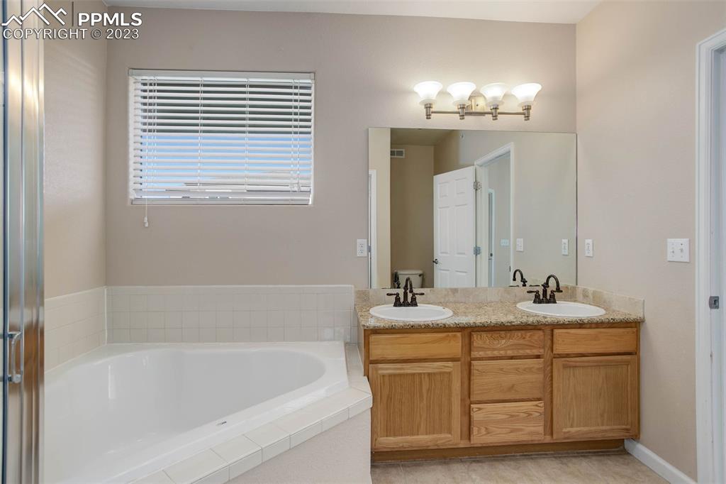 605 Cougar Bluff Point, Unit 210 Colorado Springs, CO 80906 - Photo 25 of 33 a bathroom with a sink tub double vanity and a mirror