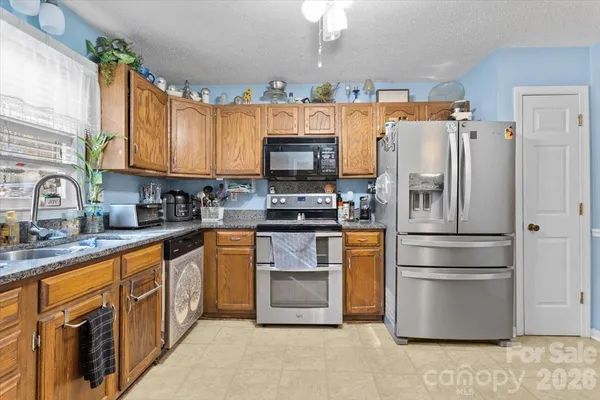 a kitchen with granite countertop a refrigerator and a stove top oven