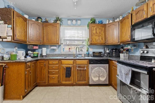 a kitchen with stainless steel appliances granite countertop a stove a sink dishwasher and a microwave oven with cabinets