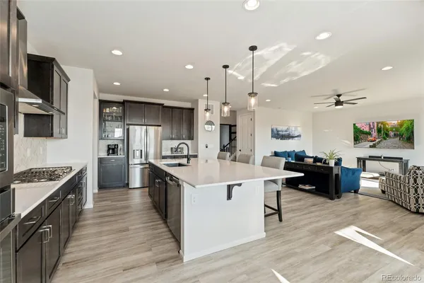 a large kitchen with stainless steel appliances kitchen island granite countertop a large stove a sink dishwasher and a refrigerator with wooden floor