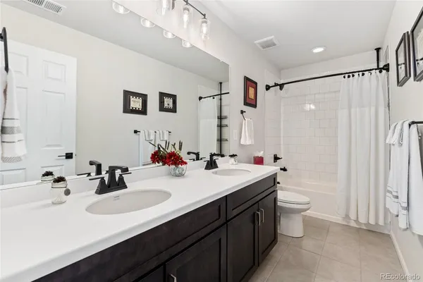 a bathroom with a double vanity sink toilet mirror and shower
