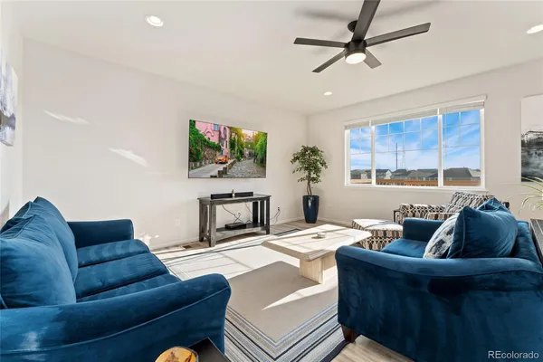 a living room with furniture a ceiling fan and a flat screen tv