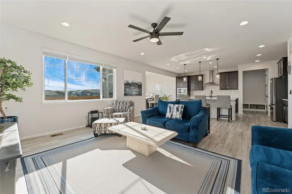 a living room with furniture kitchen area and a window