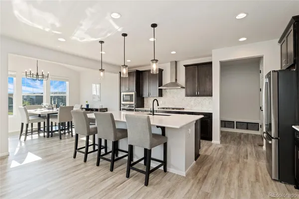 a kitchen with stainless steel appliances a dining table chairs stove refrigerator and cabinets