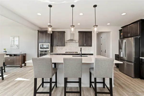 a kitchen with stainless steel appliances granite countertop a kitchen island a stove a refrigerator a kitchen island a table and chairs