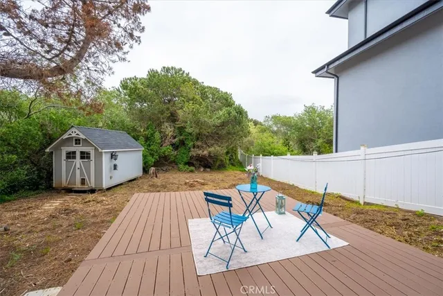 a view of a roof deck with table and chairs a barbeque with wooden floor and fence