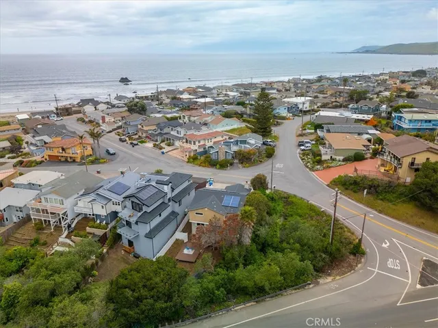 an aerial view of a city with lots of residential buildings ocean and mountain view in back
