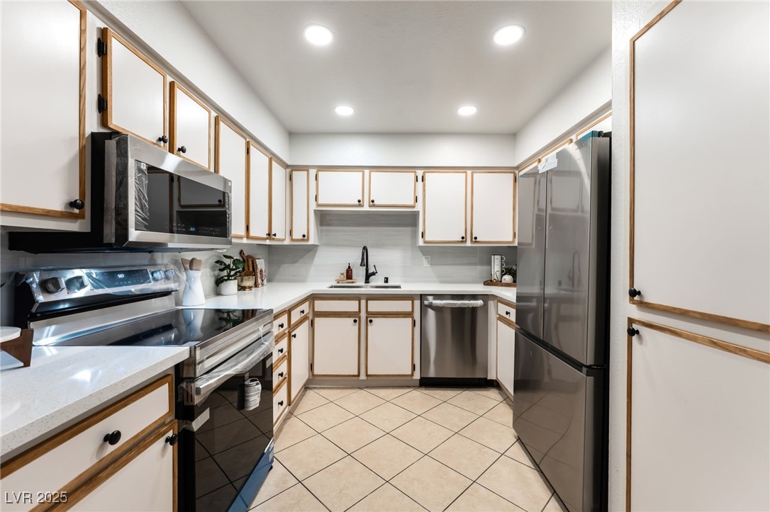 3151 North Soaring Gulls Drive, Unit 1188 Las Vegas, NV 89128 - Photo 11 of 43 Kitchen featuring appliances with stainless steel finishes, white cabinetry, light tile patterned flooring, recessed lighting, and tasteful backsplash