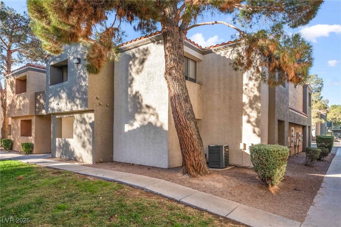 3151 North Soaring Gulls Drive, Unit 1188 Las Vegas, NV 89128 - Photo 30 of 43 View of side of property featuring a tile roof, stucco siding, and a lawn