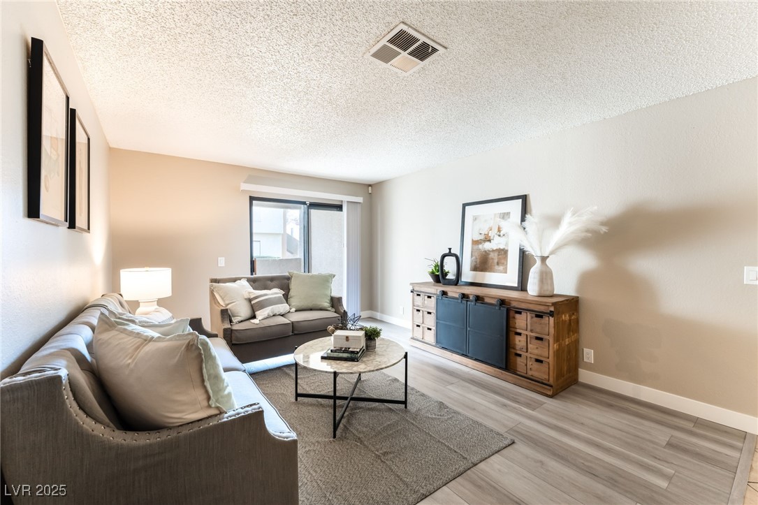 3151 North Soaring Gulls Drive, Unit 1188 Las Vegas, NV 89128 - Photo 3 of 43 Living area with a textured ceiling and light wood-style floors