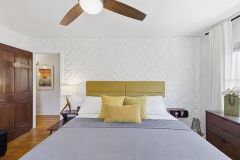 a bedroom with a bed and a potted plant on the dresser