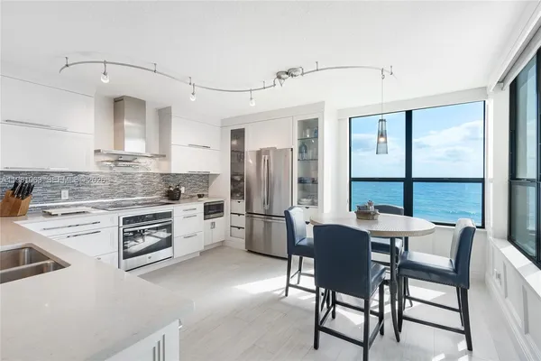 a kitchen with a dining table chairs and refrigerator