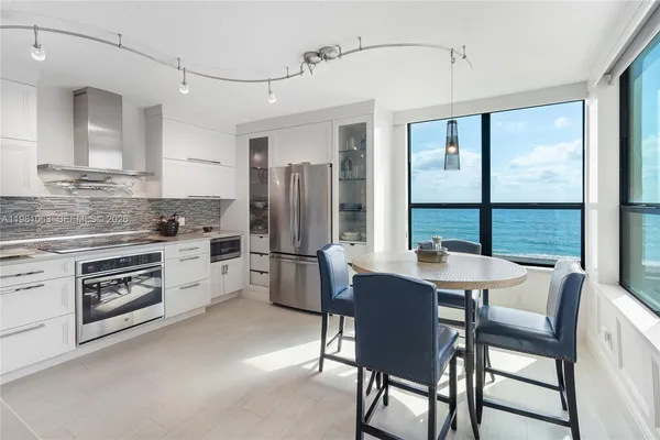 a kitchen with stainless steel appliances a stove a refrigerator a dining table and chairs