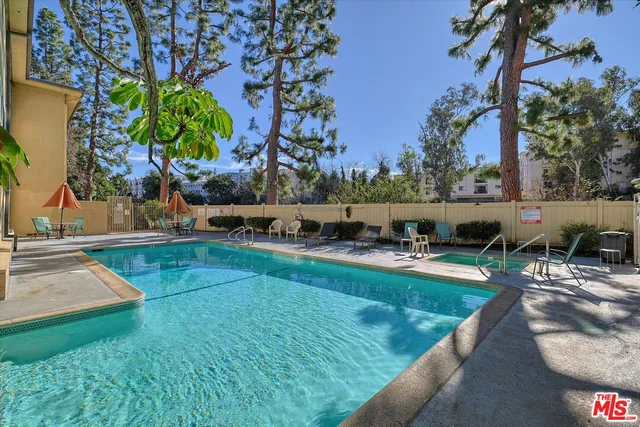 a view of a backyard with lawn chairs potted plants and swimming pool