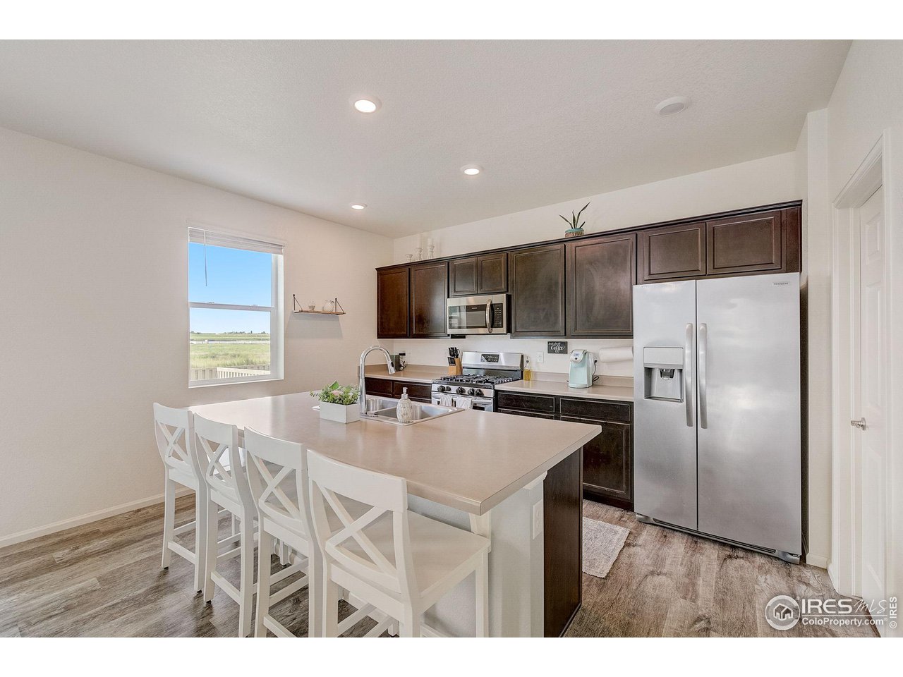 327 Central Avenue Severance, CO 80550 - Photo 9 of 40 a kitchen with stainless steel appliances a refrigerator a stove a sink dishwasher with a dining table and chairs