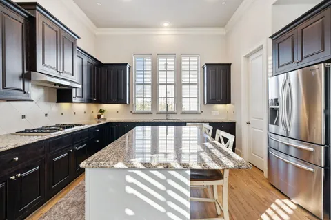 a kitchen with granite countertop a refrigerator a sink and wooden cabinets