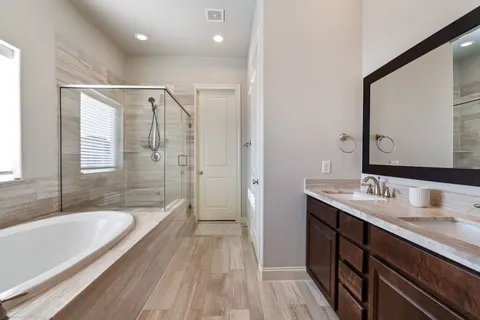 a bathroom with a granite countertop tub sink shower and mirror