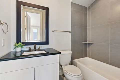 a bathroom with a granite countertop toilet sink and mirror