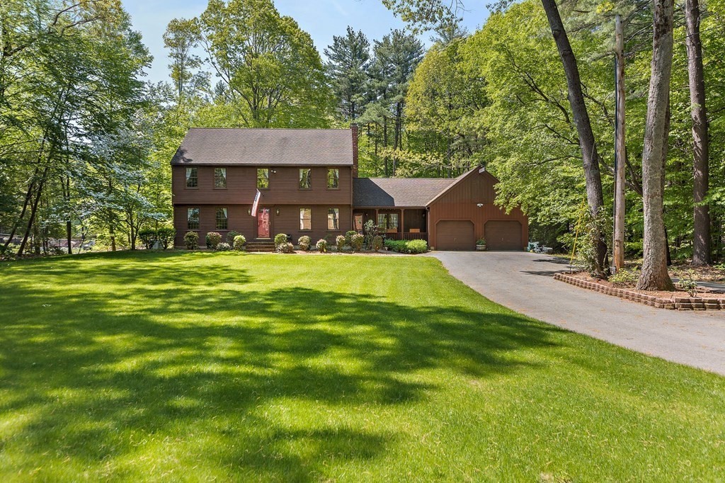 a view of a house with a big yard potted plants and large tree