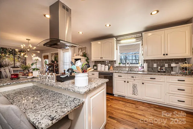 a kitchen with stainless steel appliances granite countertop a stove top oven a sink a counter space and living room view