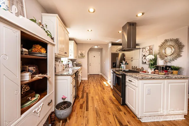 a kitchen with stainless steel appliances kitchen island granite countertop a stove a sink and a refrigerator