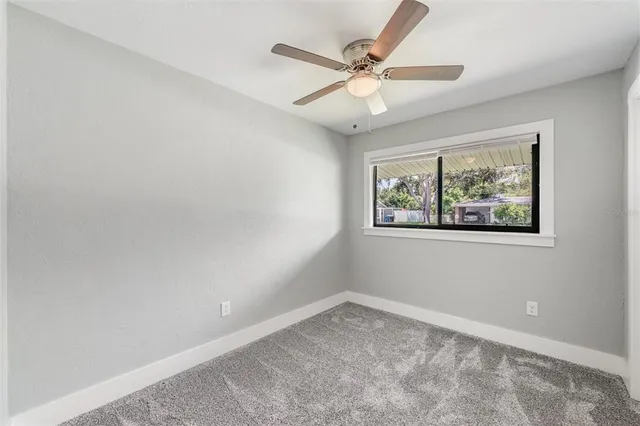 an empty room with a window and a fan