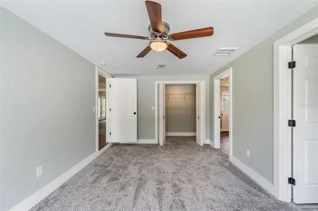a view of empty room with wooden floor and ceiling fan
