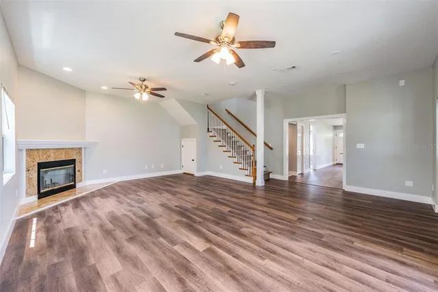 a view of an empty room with wooden floor fireplace and a window