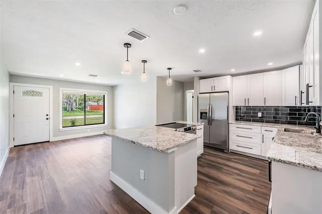 a large kitchen with stainless steel appliances kitchen island granite countertop a stove and a sink