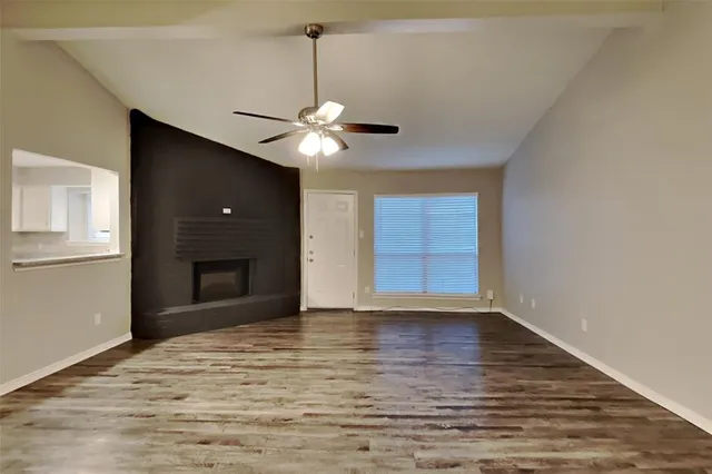 a view of an empty room with a window and chandelier fan