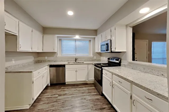 a kitchen with granite countertop white cabinets sink and stainless steel appliances