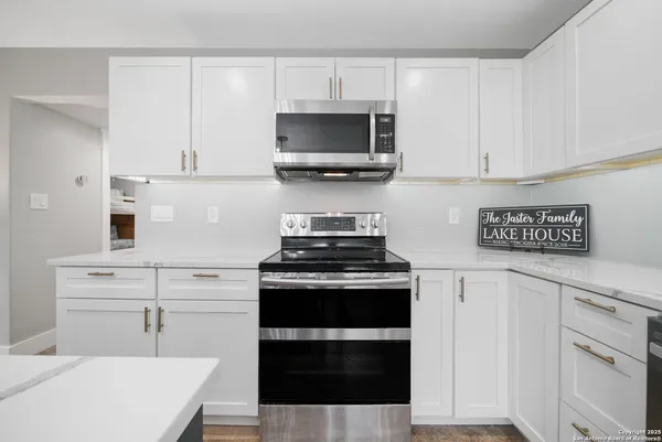 a large living room with stainless steel appliances granite countertop couches a flat screen tv and a refrigerator