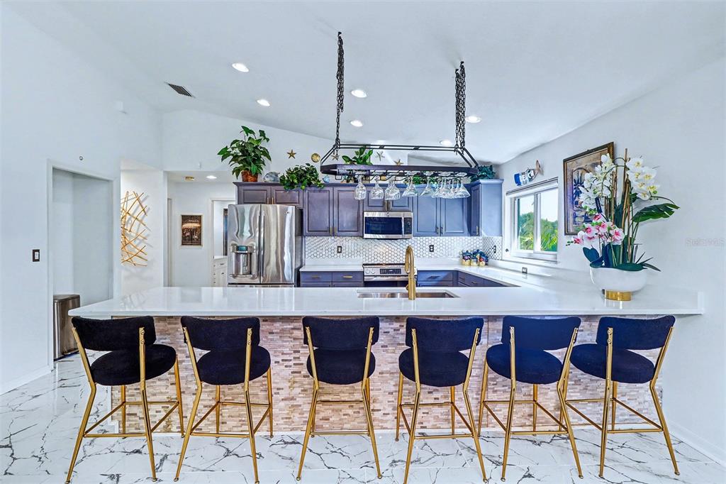 15517 Gulf Boulevard Redington Beach, FL 33708 - Photo 11 of 48 a kitchen with stainless steel appliances kitchen island granite countertop a table and chairs in it