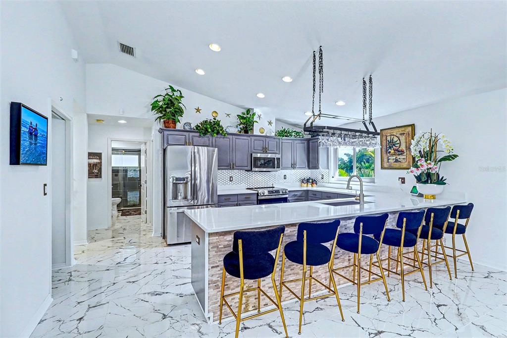 15517 Gulf Boulevard Redington Beach, FL 33708 - Photo 10 of 48 a kitchen with stainless steel appliances kitchen island granite countertop a table chairs and white cabinets