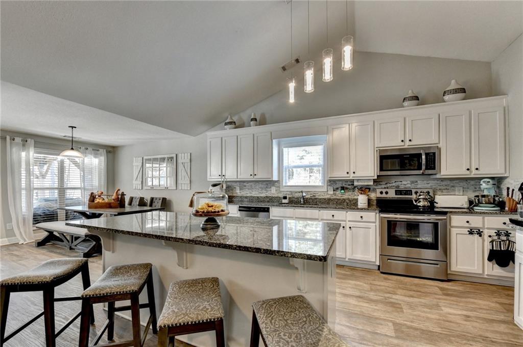 204 Lynn Road Bethlehem, GA 30620 - Photo 12 of 44 a kitchen with stainless steel appliances granite countertop a stove top oven a sink dishwasher a dining table and chairs with wooden floor
